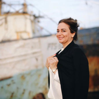 Female teacher dressed in a black and white jacket paired with a white shirt, showcasing a polished and academic appearance.